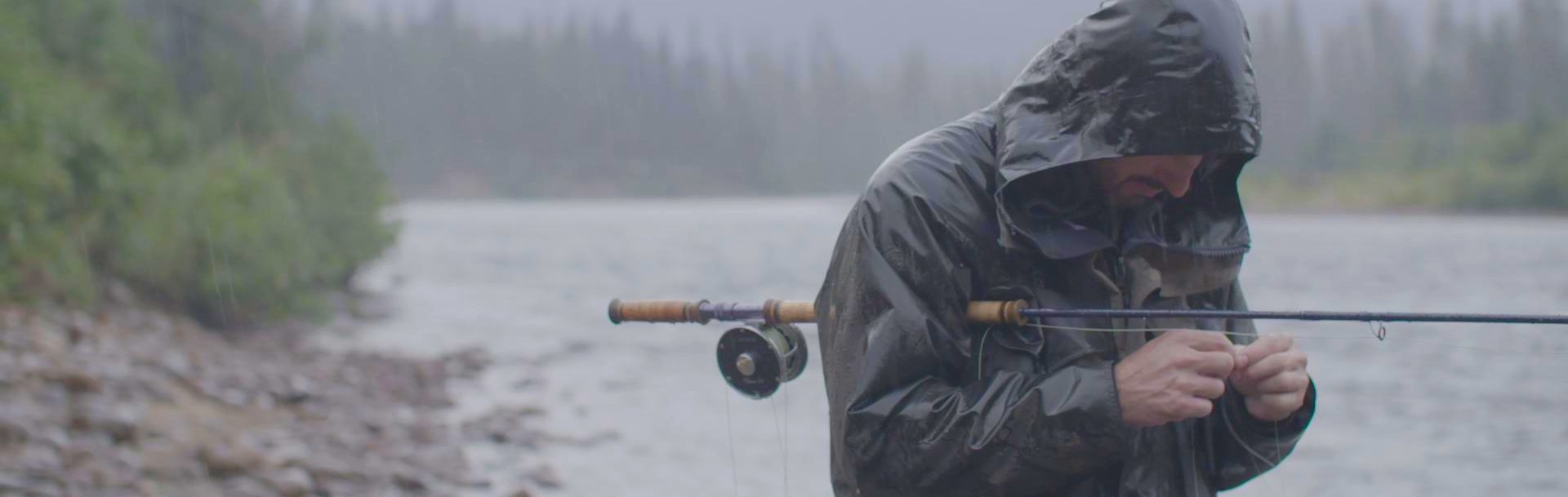 A man in the rain tying a fly to his rod